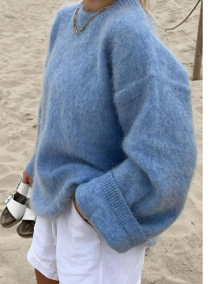 Frau in blauem, oversized Strickpullover aus Wolle, Strandhintergrund, modisch, Herbst 2023.