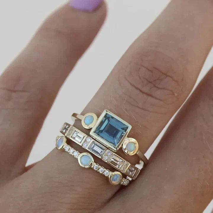 Goldene Ringe mit blauem Edelstein und Diamanten auf Finger, eleganter Schmuck, Nahaufnahme.