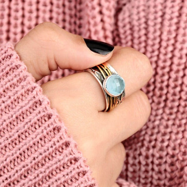 Damenring mit blauem Edelstein, Silber und Gold, modisches Accessoire, gestrickter Pullover.
