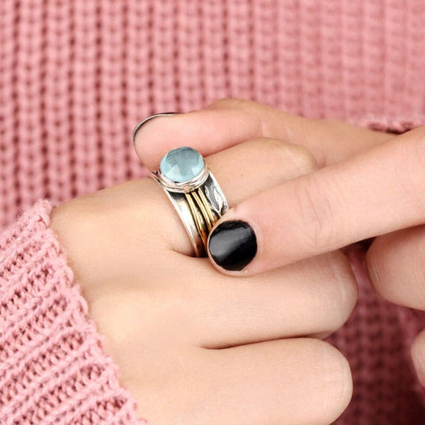 Silberring mit blauem Edelstein, Damenmode, eleganter Schmuck, gestrickter rosa Pullover.