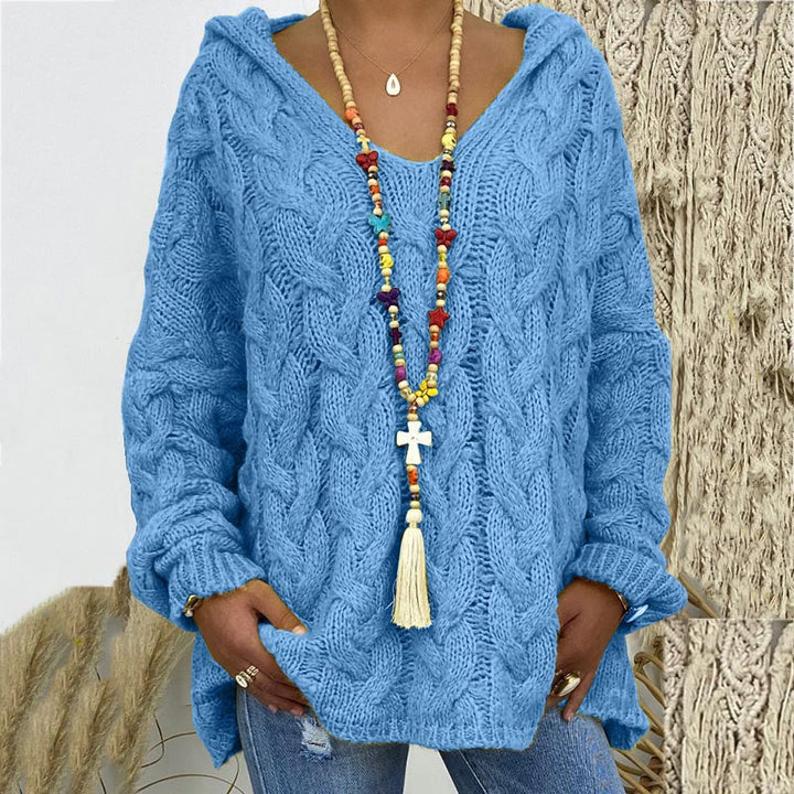 Frau in blauem Strickpullover mit Kapuze und bunter Halskette aus Holzperlen.