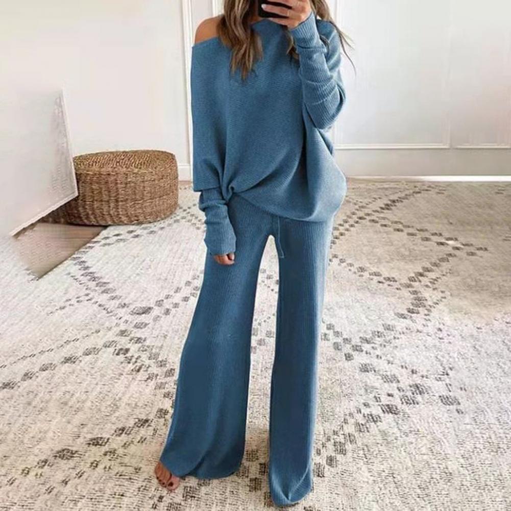 Frau in blauem Strickpullover und Hose, gemütliches Lounge-Set, modernes Wohnzimmer.