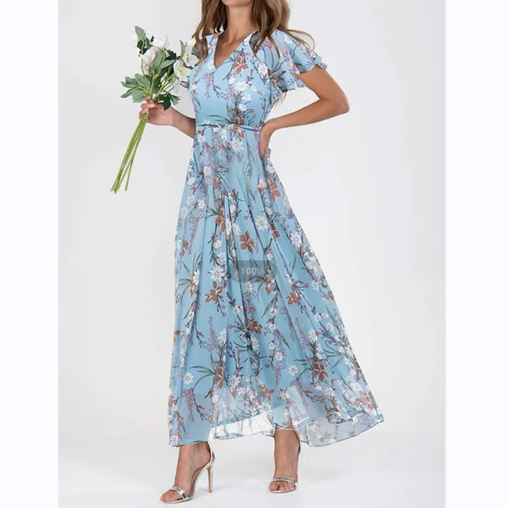 Frau in blauem, geblümtem Maxikleid mit Blumenstrauß, elegante Sommermode.