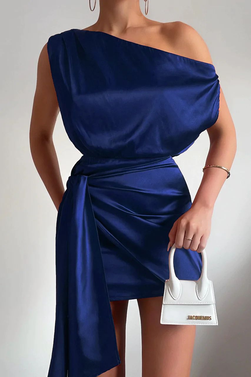 Frau in blauem Satin-One-Shoulder-Kleid mit weißer Mini-Handtasche, elegantes Abendoutfit.