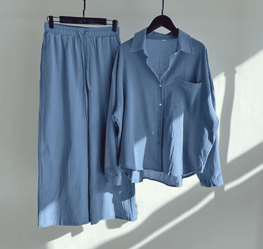 Hellblaues Damen-Pyjama-Set aus Baumwolle, bestehend aus Hemd und Hose, auf Kleiderbügeln.