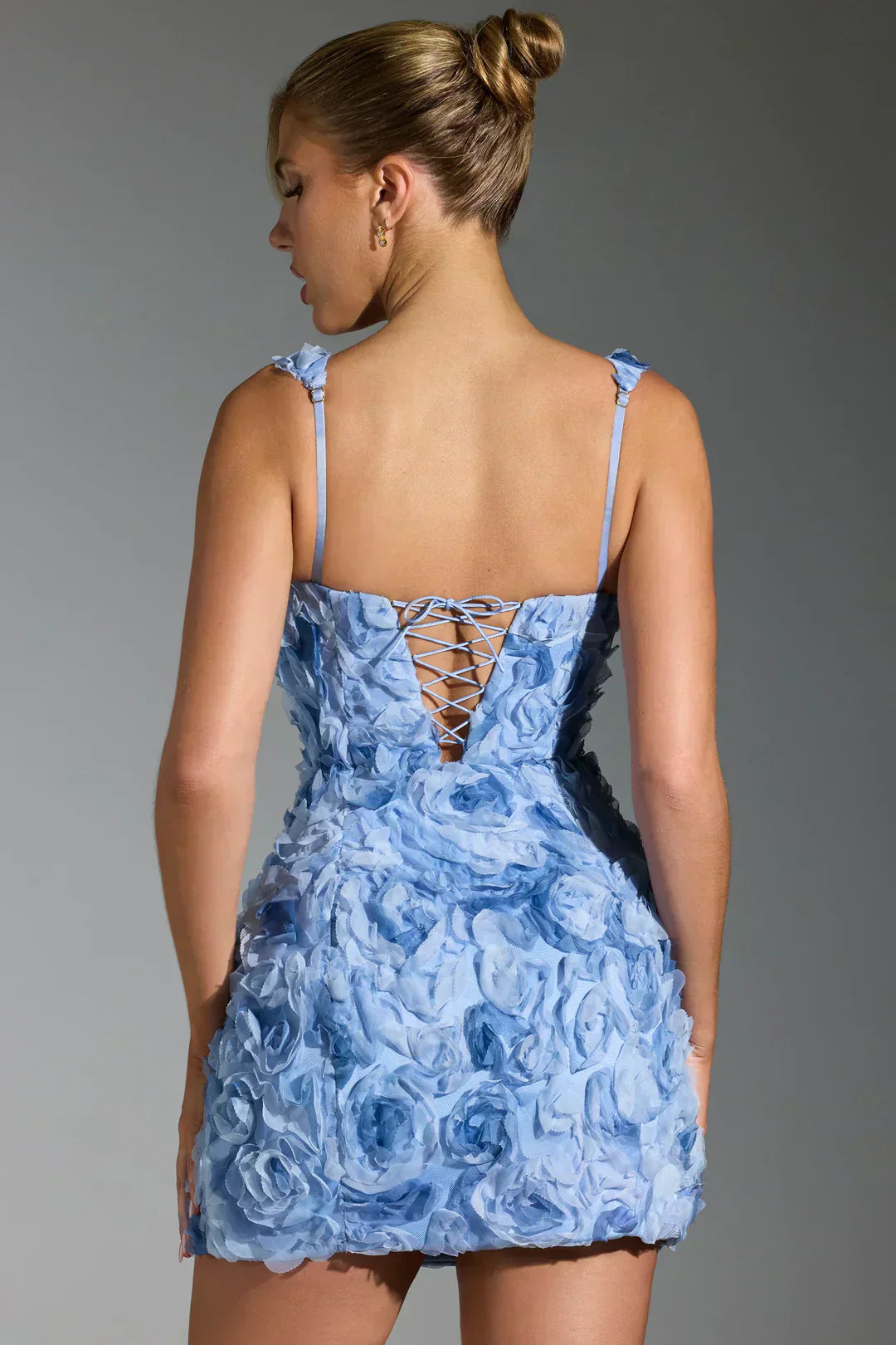 Frau in blauem Blumenkleid mit Schnürung, elegantes Abendkleid, modisches Design.