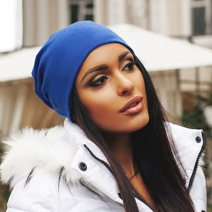 Frau mit blauer Beanie-Mütze und weißer Winterjacke, stilvolle Wintermode.