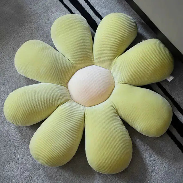 Gelbes Blumenkissen aus Cord auf grauem Teppich, dekoratives Wohnaccessoire, gemütlich.