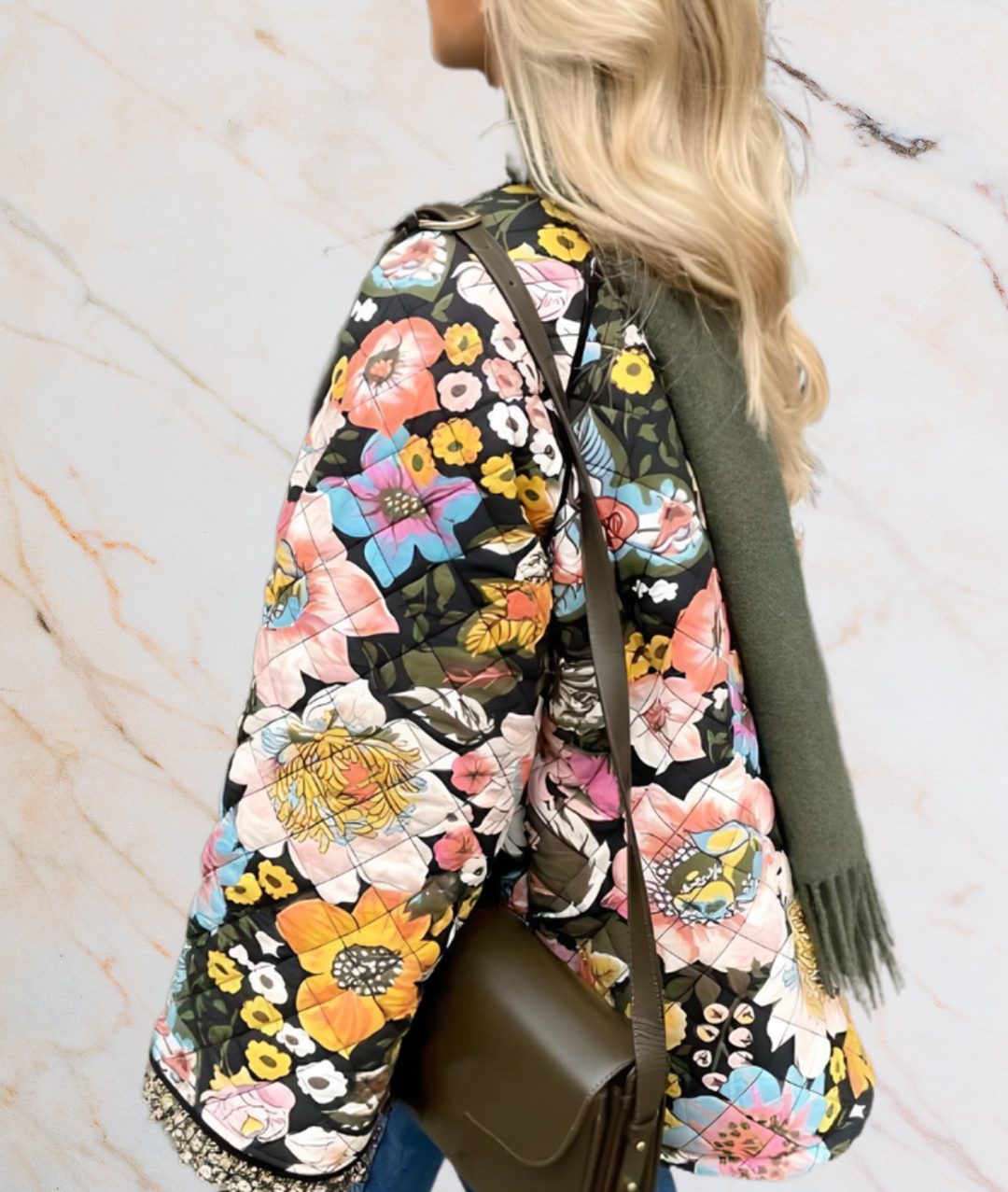 Frau mit bunter Blumenjacke, olivgrüner Schal, braune Umhängetasche, Marmorhintergrund.