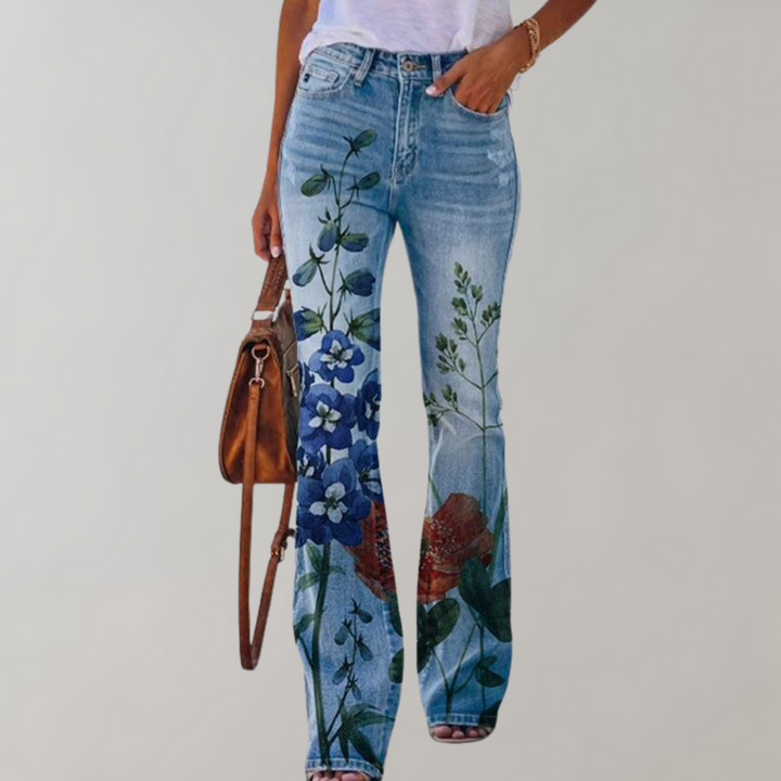 Frau in blauer Jeans mit Blumenmuster, weißem T-Shirt und brauner Tasche.