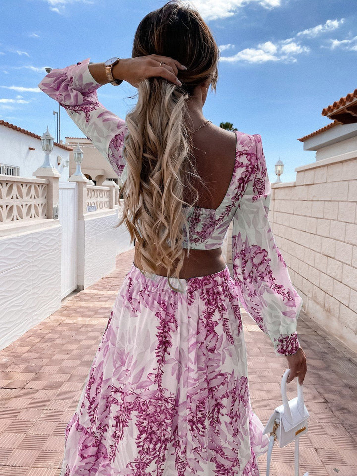 Frau in langem, geblümtem Kleid mit rosa Muster, hält weiße Handtasche, Sommermode.