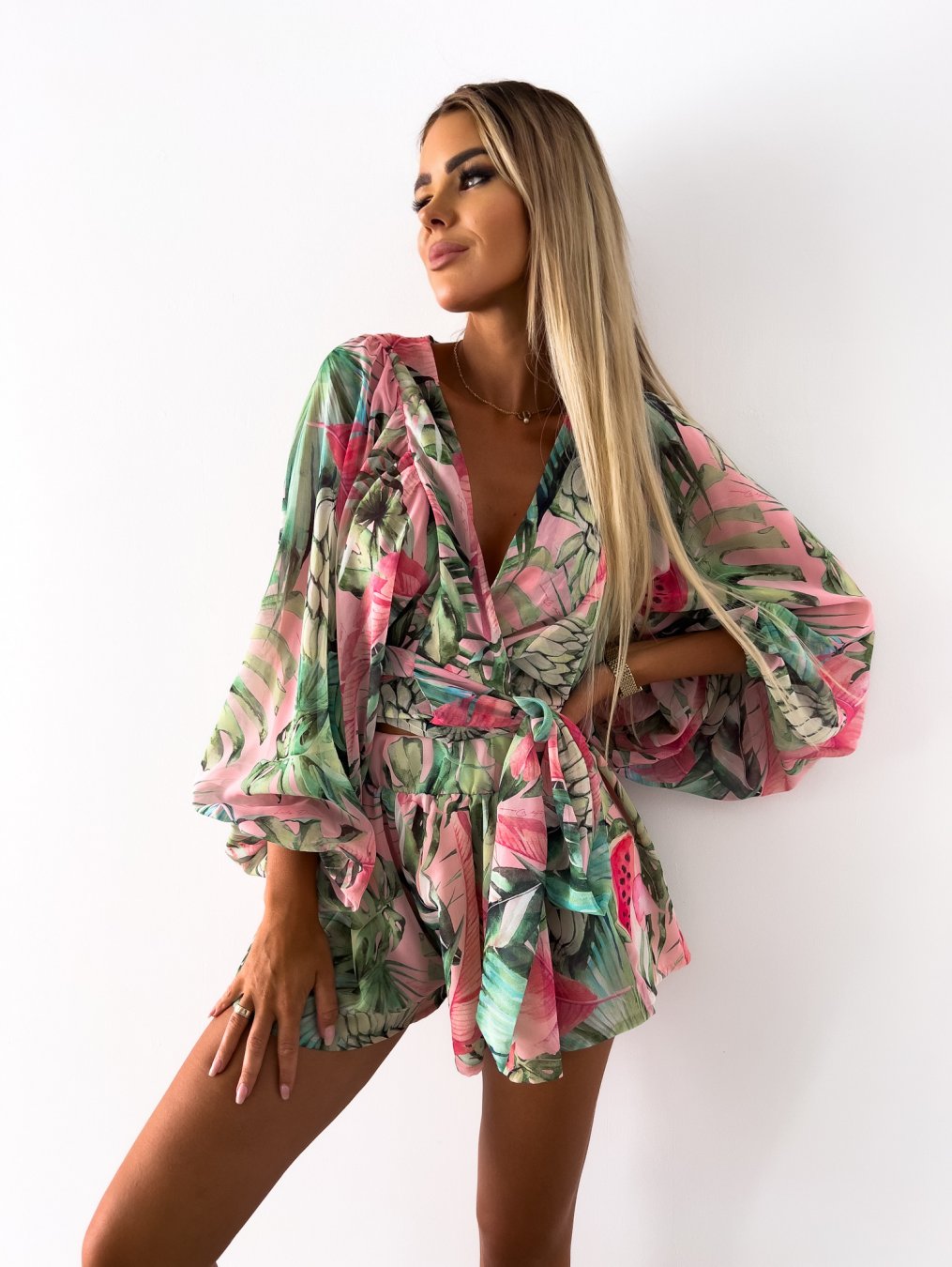 Frau in grün-rosa tropischem Jumpsuit, Sommermode, florales Design, elegante Kleidung.