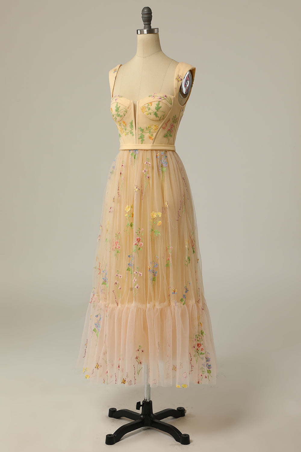 Beiges, ärmelloses Kleid mit Blumenstickerei auf Schneiderpuppe, Tüllrock, elegantes Design.