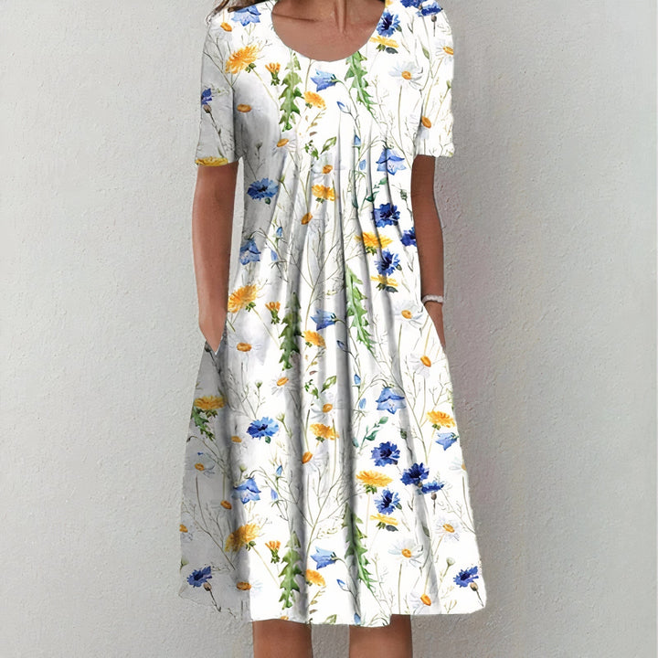 Frau in weißem Sommerkleid mit Blumenmuster, kurzärmelig, knielang, lässig, elegant.
