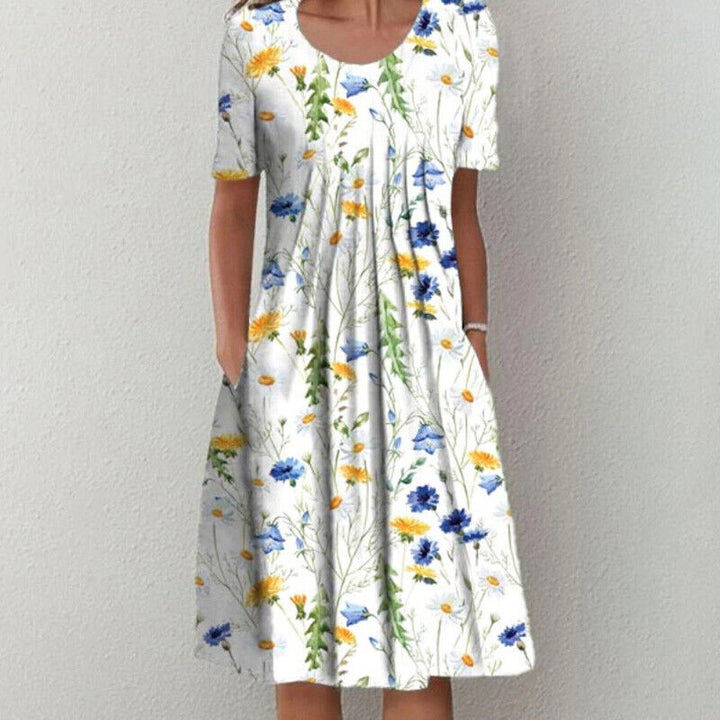 Frau in weißem Sommerkleid mit buntem Blumenmuster, kurzärmelig, knielang.