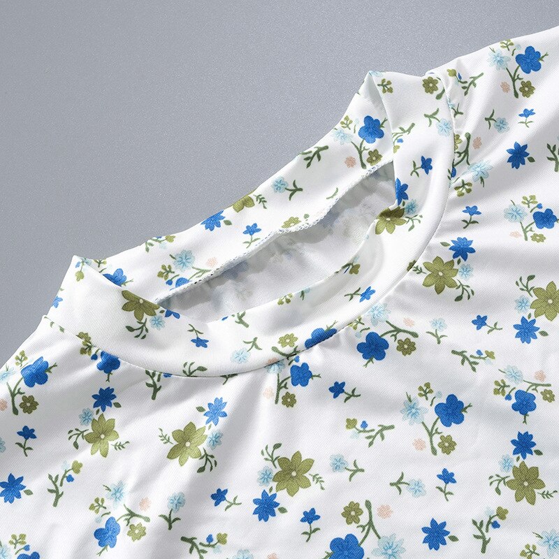 Weiße Bluse mit blau-grünem Blumenmuster, Rundhalsausschnitt, Damenmode, Frühlingstrend.