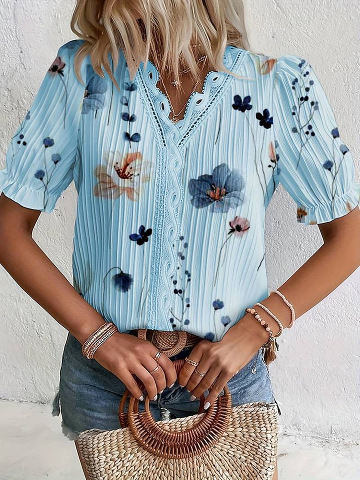 Frau in blauer Blumenbluse mit Spitzenkragen, Jeansshorts, Strohtasche, Sommermode.