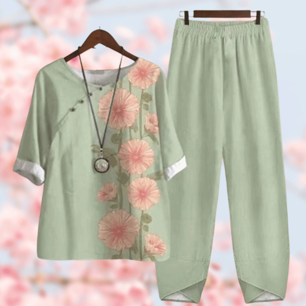 Grünes Damen-Leinen-Set mit Blumenmuster, bestehend aus Bluse und Hose, vor Kirschblüten.