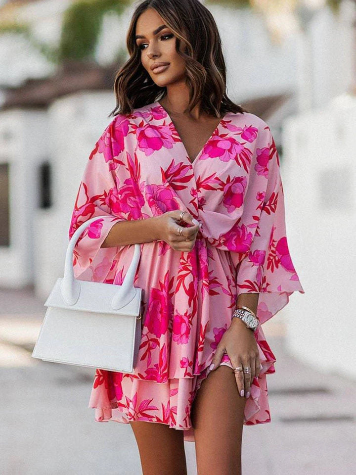Frau in rosa Blumenkleid mit weißer Handtasche, modisch, Sommermode, elegantes Outfit.