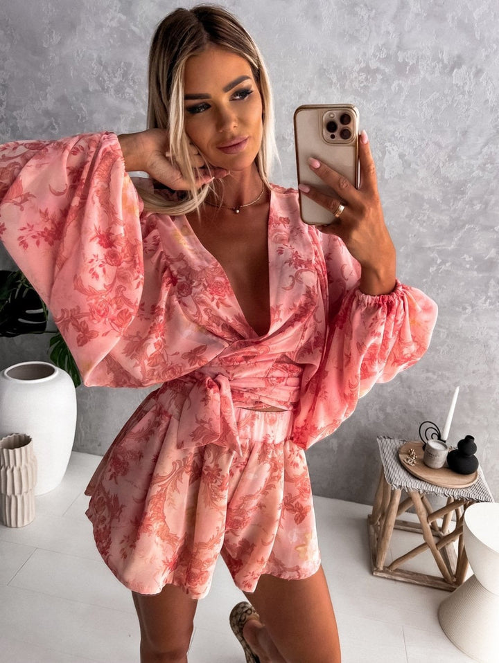 Frau in rosa Blumenkleid mit weiten Ärmeln, Selfie, modernes Interieur, Smartphone.