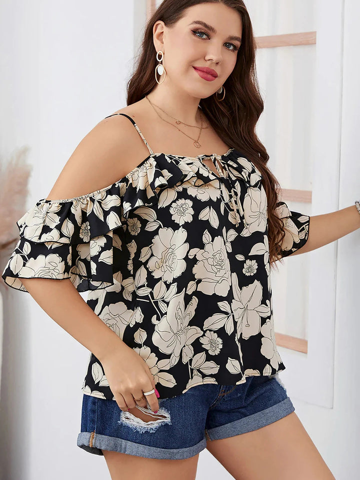 Frau in schwarzer Blumenbluse mit Rüschen und Jeansshorts, Sommermode, Plus-Size-Outfit.