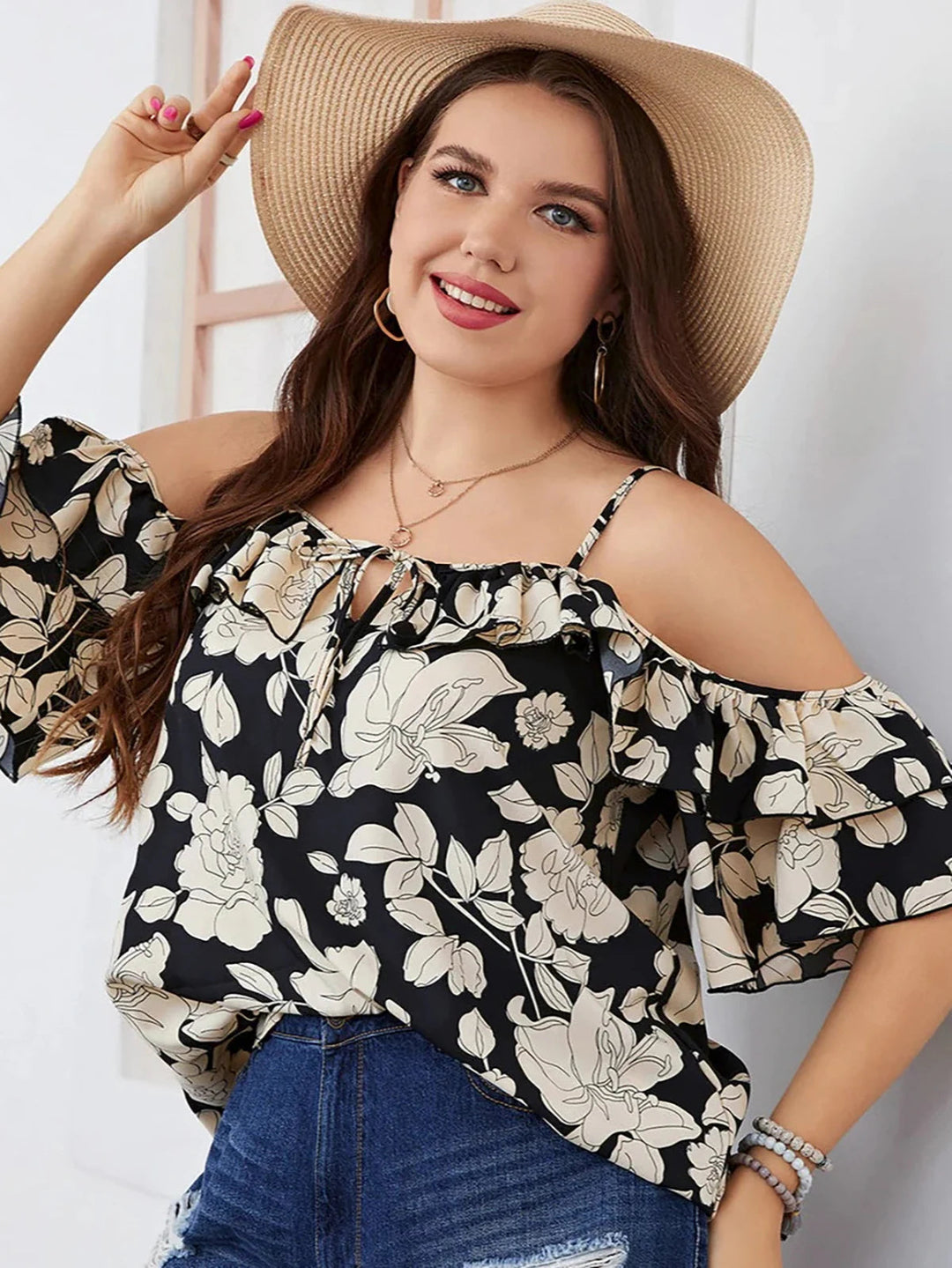 Frau in schwarzer, geblümter Bluse und Strohhut, lächelnd, Sommermode, Freizeitkleidung.