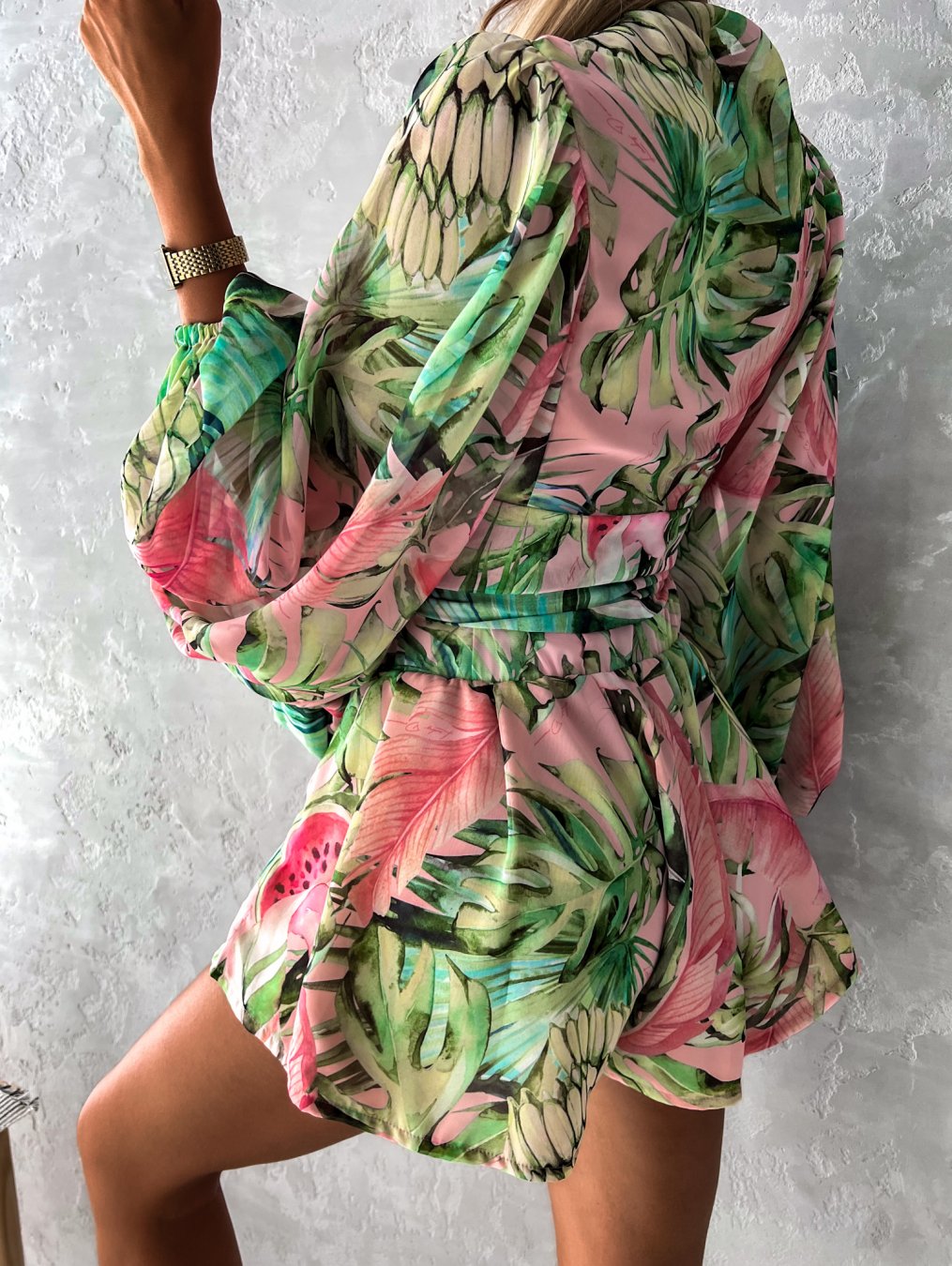 Frau in grün-rosa tropischem Kleid, langärmelig, Sommermode, florales Muster.