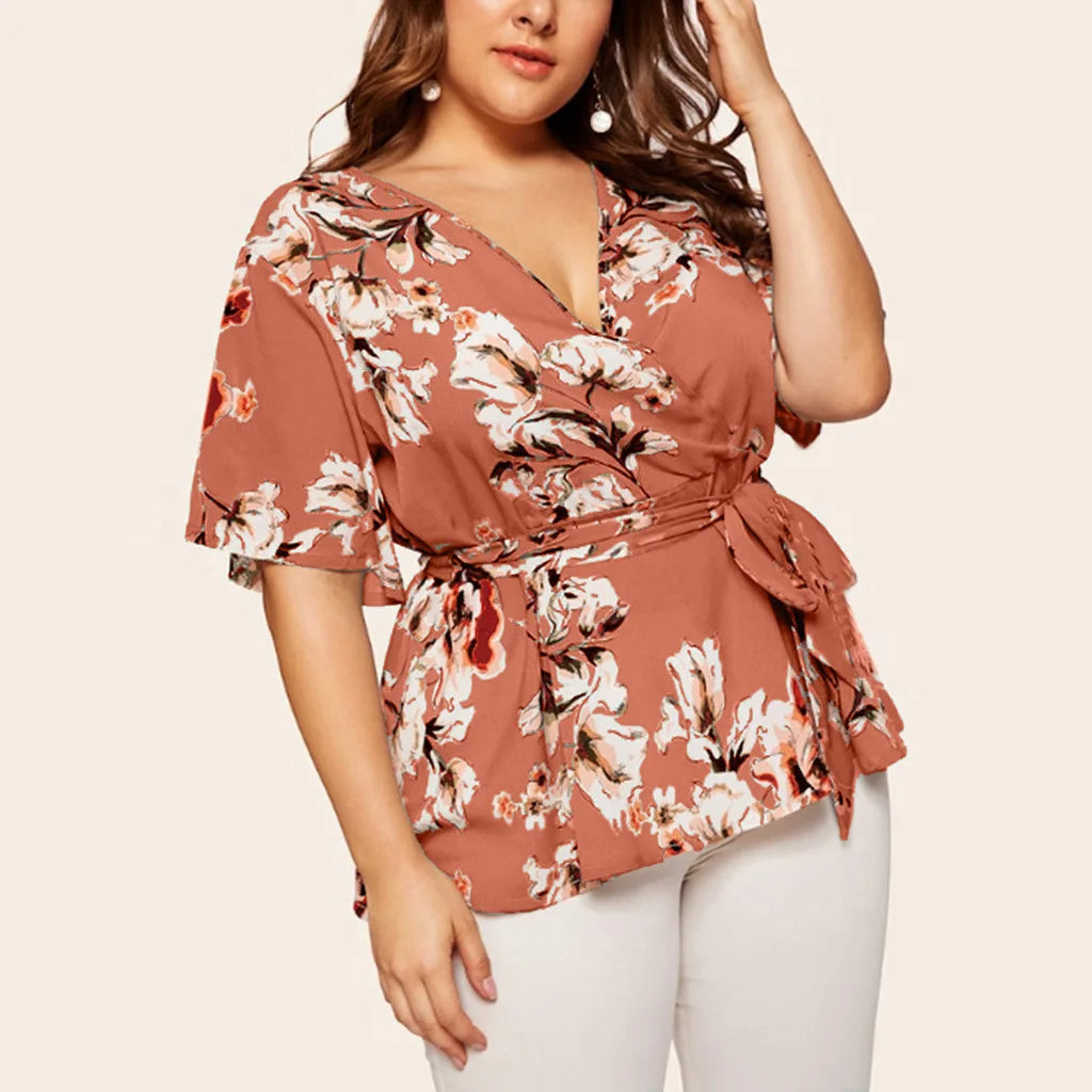 Frau in geblümter Wickelbluse, rosa, V-Ausschnitt, kurze Ärmel, modisch, elegant.