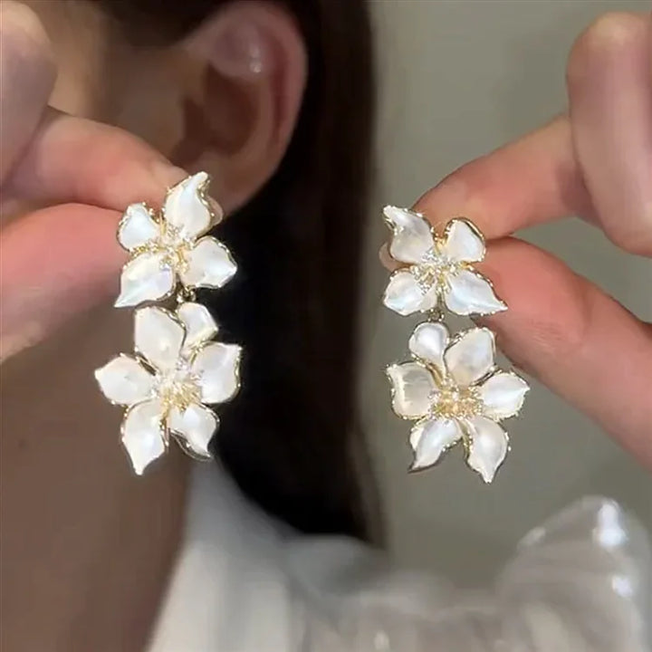 Weiße Blumenohrringe, Perlmutt, goldene Akzente, eleganter Schmuck, Damenaccessoire.