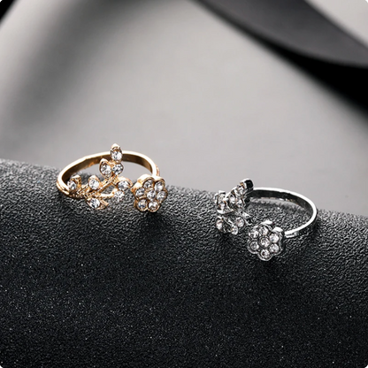 Zwei elegante Blumenringe, gold und silber, mit funkelnden Kristallen auf schwarzem Hintergrund.