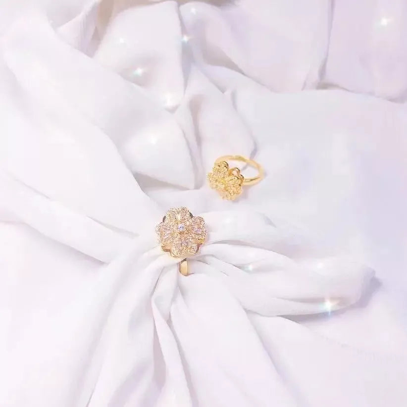 Goldener Blumenring mit Diamanten auf weißem Stoff, eleganter Schmuck, luxuriöses Design.