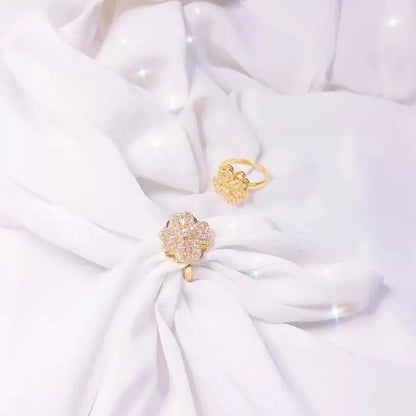 Goldener Blumenring mit Diamanten auf weißem Stoff, eleganter Schmuck, luxuriöses Design.