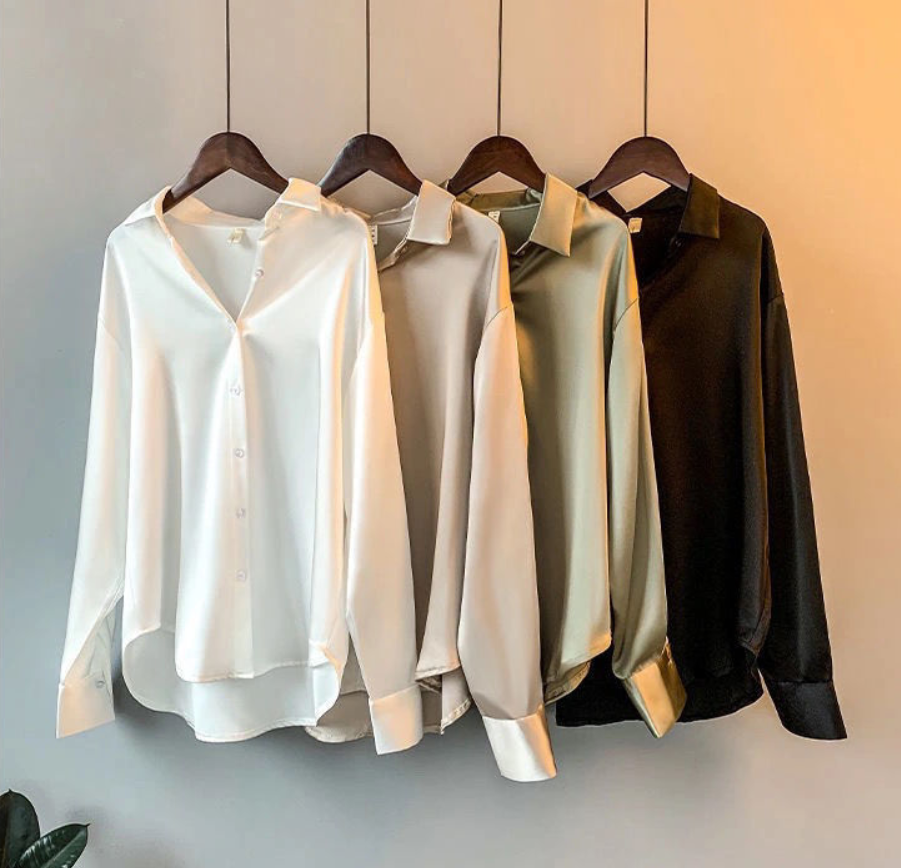 Vier elegante Damenblusen auf Kleiderbügeln, in Weiß, Beige, Grün und Schwarz.