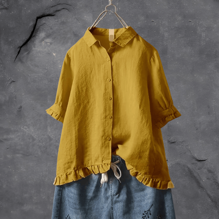 Gelbe Leinenbluse mit Rüschen, Damenmode, lässig, Sommer, auf grauem Hintergrund.