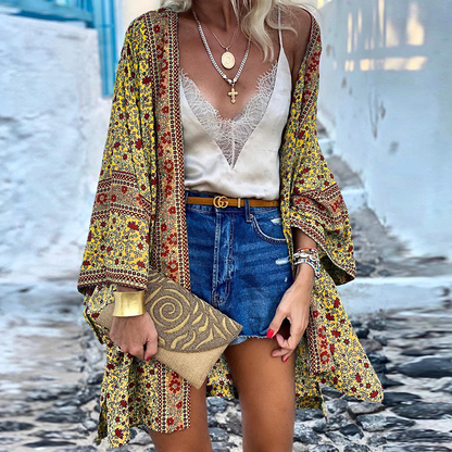 Frau in gelbem Kimono mit Blumenmuster, Jeansshorts, Spitzen-Top, goldene Accessoires, Sommermode.