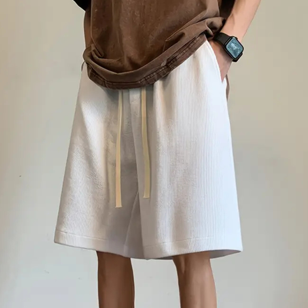 Person in weißen Shorts mit Kordelzug, braunes T-Shirt, Armbanduhr, lässiger Stil.