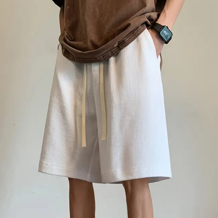 Person in weißen Shorts mit Kordelzug, braunes T-Shirt, Armbanduhr, lässiger Stil.