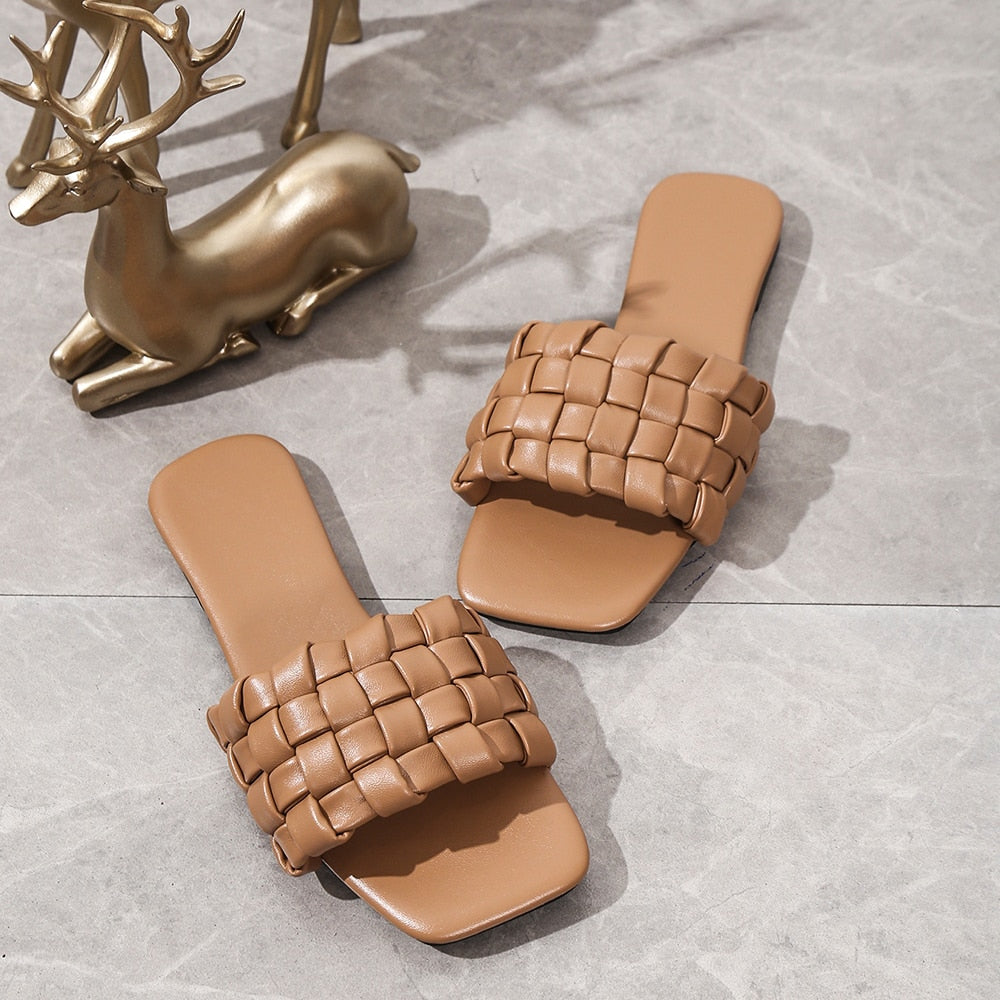 Braune geflochtene Sandalen für Damen, flach, modisch, ideal für Sommer, auf grauem Hintergrund.