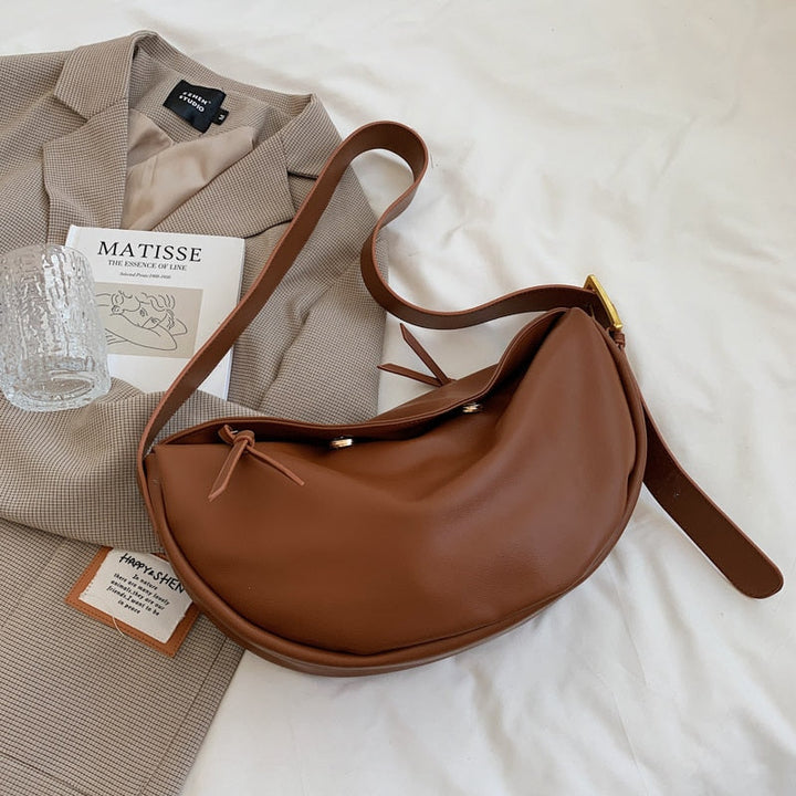 Braune Leder-Umhängetasche auf beigem Blazer, stilvoll, modern, Damenmode Accessoire.