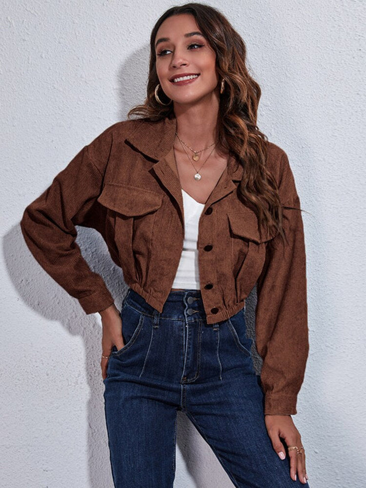 Frau trägt braune Jacke, weiße Bluse, blaue Jeans; modische Damenbekleidung, Freizeitlook.