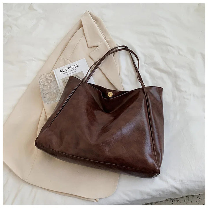 Braune Ledertasche auf beigem Mantel, elegantes Design, Damenmode Accessoire, stilvoll und praktisch.
