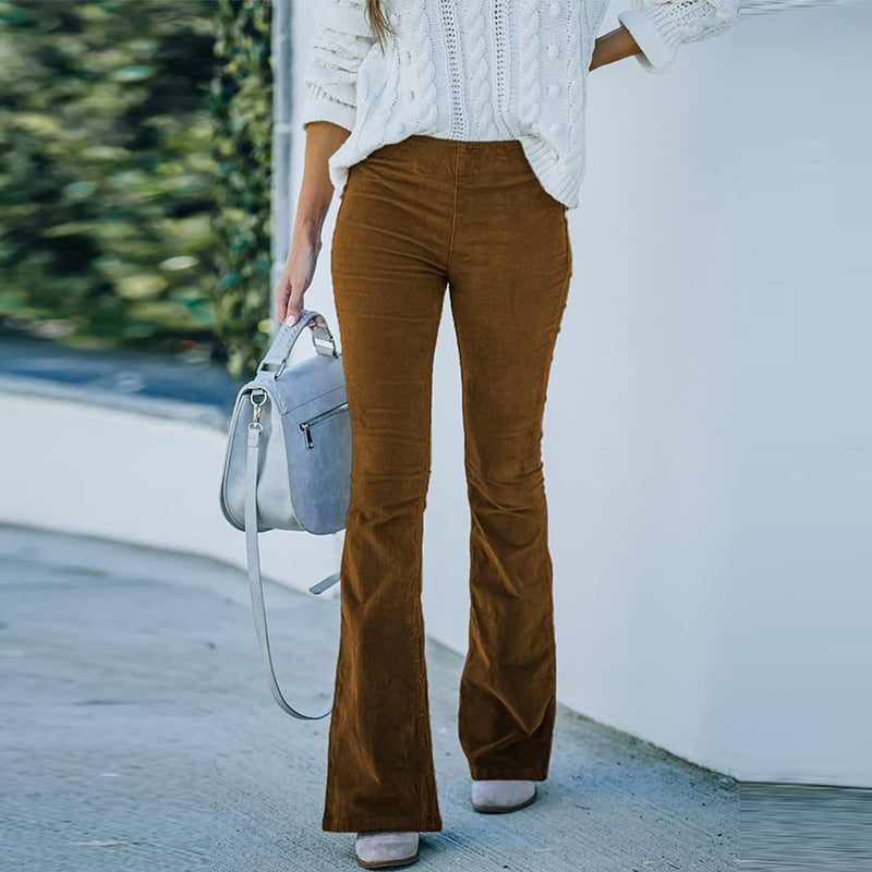 Frau in brauner Cordhose und weißem Strickpullover mit grauer Handtasche, Herbstmode.