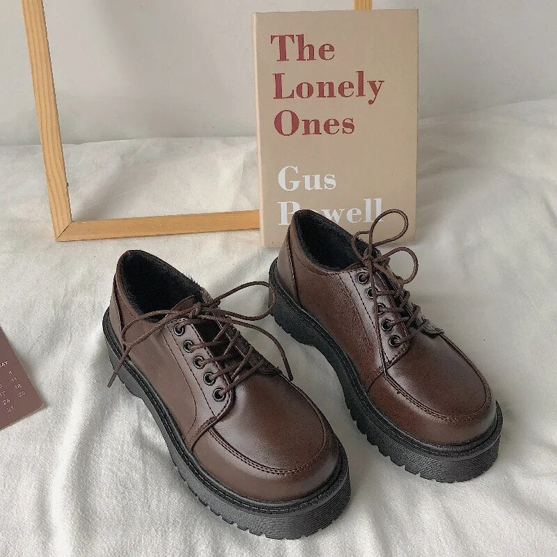 Braune Leder-Derby-Schuhe mit dicker Sohle vor Buch "The Lonely Ones" auf weißem Hintergrund.