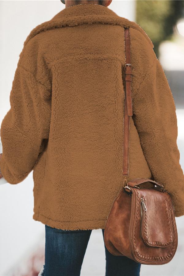 Frau in brauner Teddyjacke mit brauner Ledertasche, Herbstmode, Rückansicht.