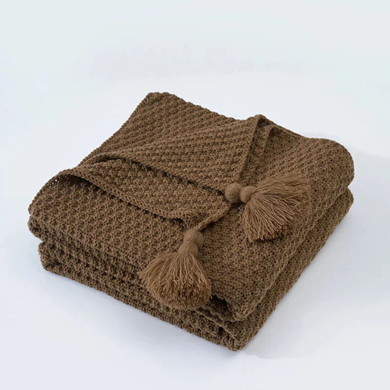 Braune Strickdecke mit Quasten, weiches Baumwollmaterial, gemütliche Wohnaccessoires.