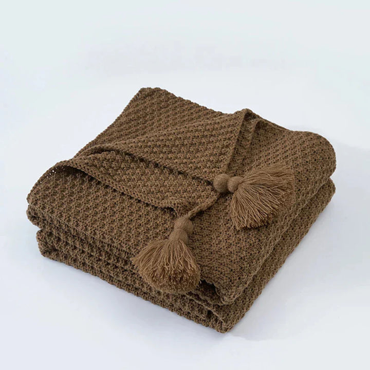 Braune Strickdecke mit Quasten, weiches Baumwollmaterial, gemütliche Wohnaccessoires.