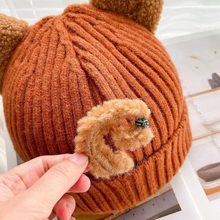 Braune Strickmütze mit Bärenohren, handgehalten, weiches Material, modisches Accessoire.