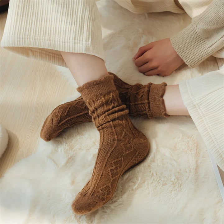 Braune Stricksocken aus Wolle, gemütlich, warm, ideal für Herbst und Winter, auf Teppich.