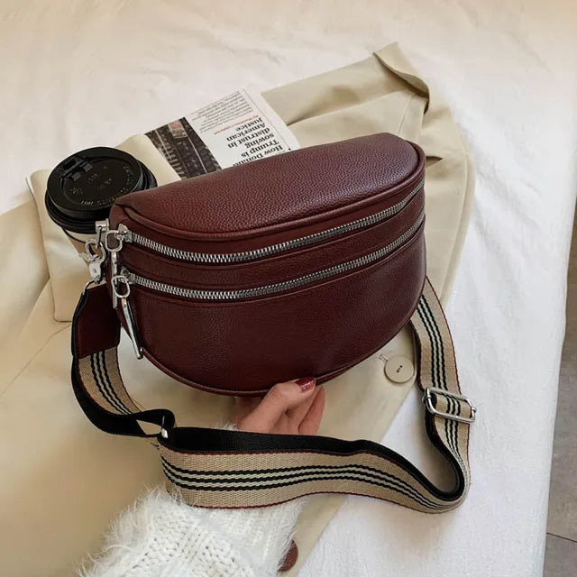 Braune Damen-Umhängetasche aus Leder mit breitem Schulterriemen und Reißverschlüssen.