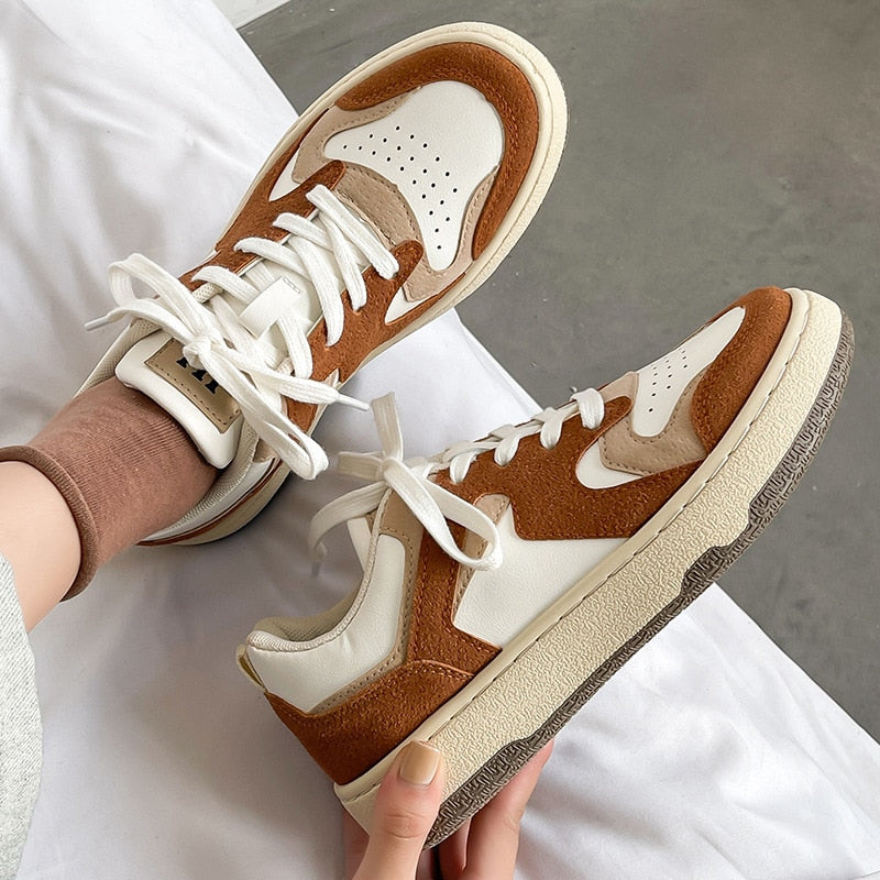 Braune und weiße Sneaker aus Leder, modisch, bequem, für Damen, auf grauem Hintergrund.